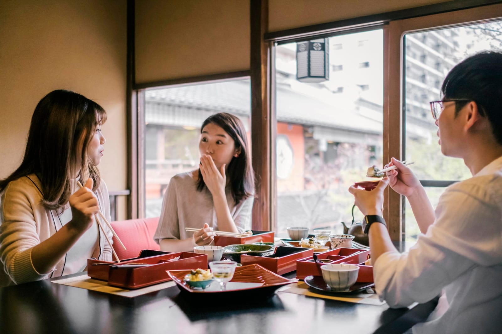 座敷で三人が食事を囲んでいる様子。